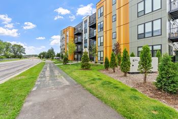 A long concrete pathway leads to a row of modern apartment buildings.